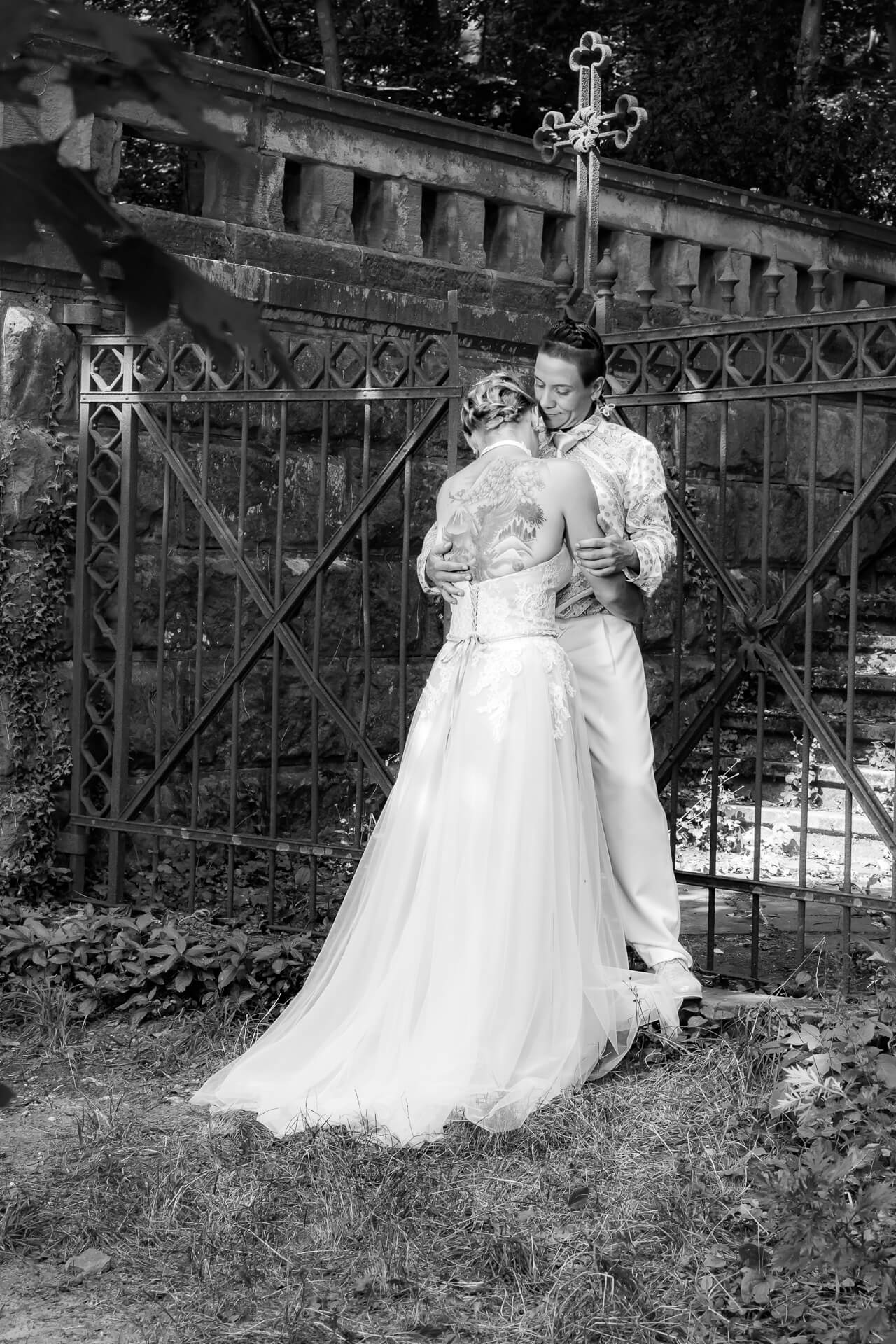 Brautpaar vor schmiedeeisernem Tor im Wald auf Treppe